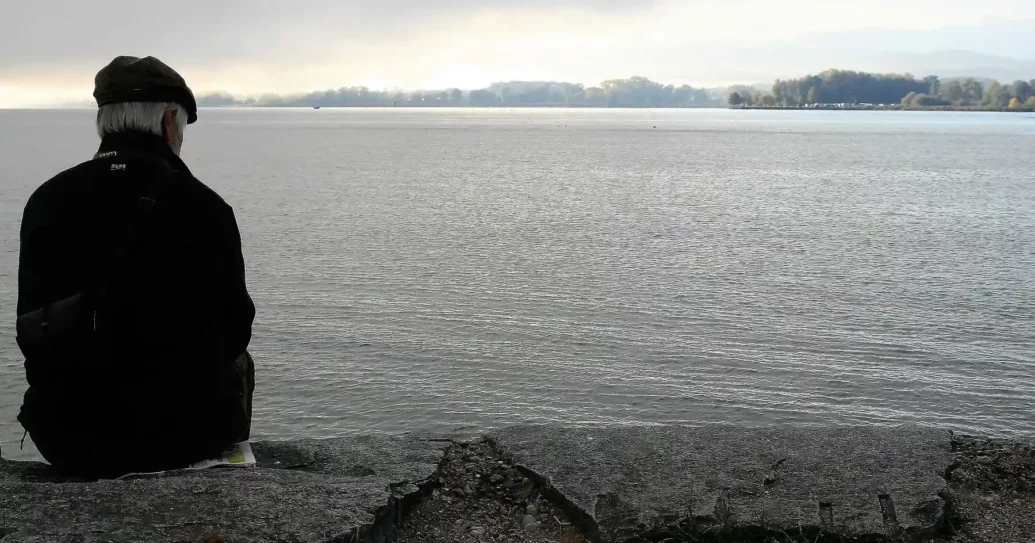 Alter Mann sitzt am Meer